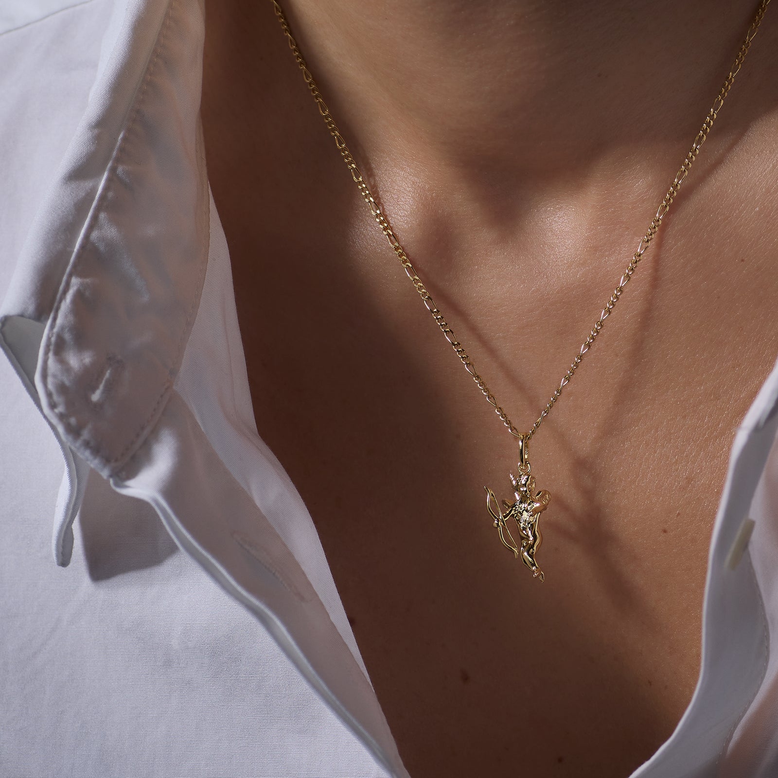Gold necklace with an Eros Angel pendant worn by a person against a neutral background