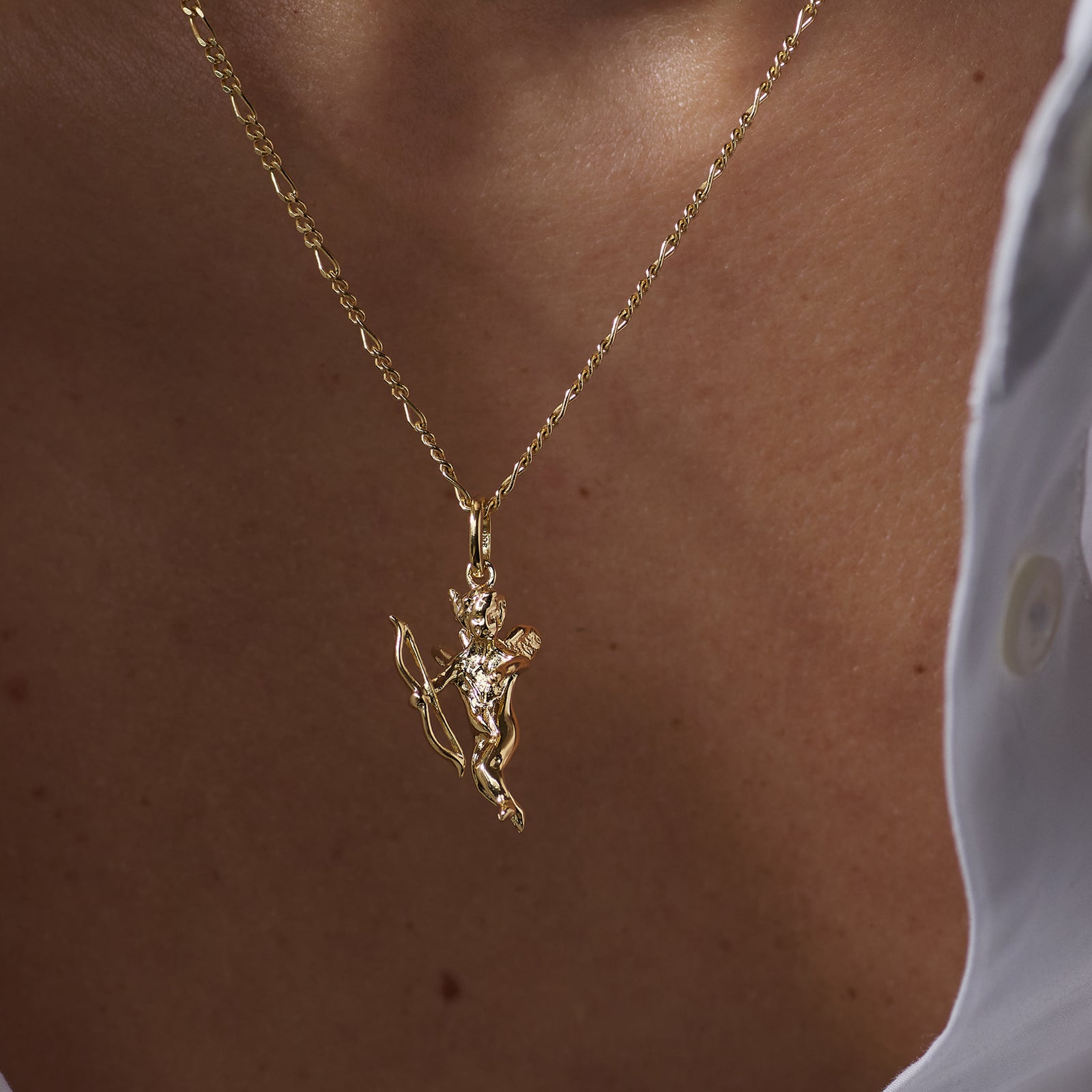 Gold necklace with an Eros Angel pendant worn by a person against a neutral background