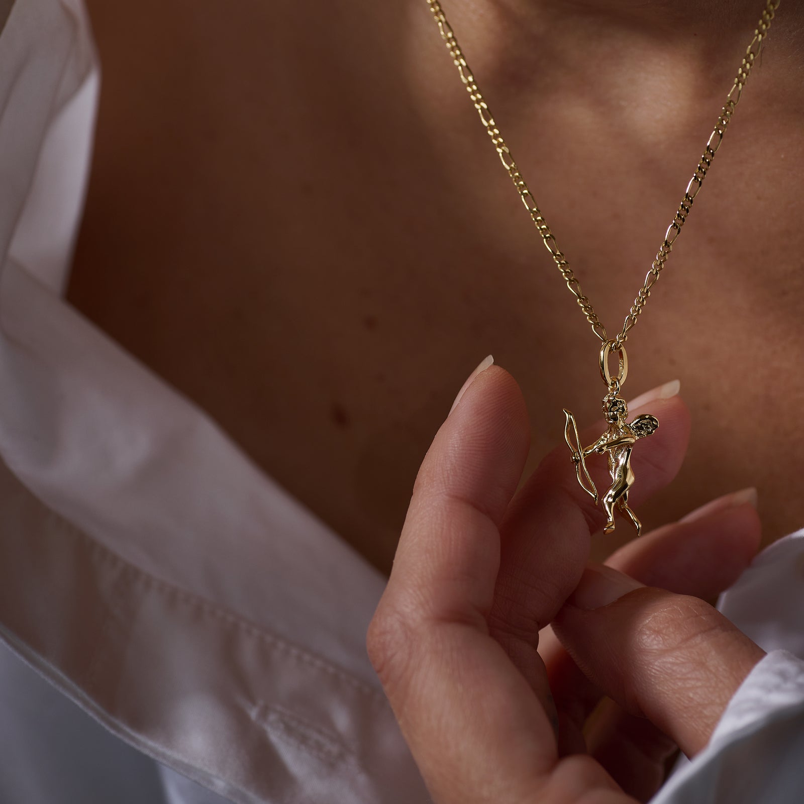 Gold necklace with an Eros Angel pendant worn by a person against a neutral background
