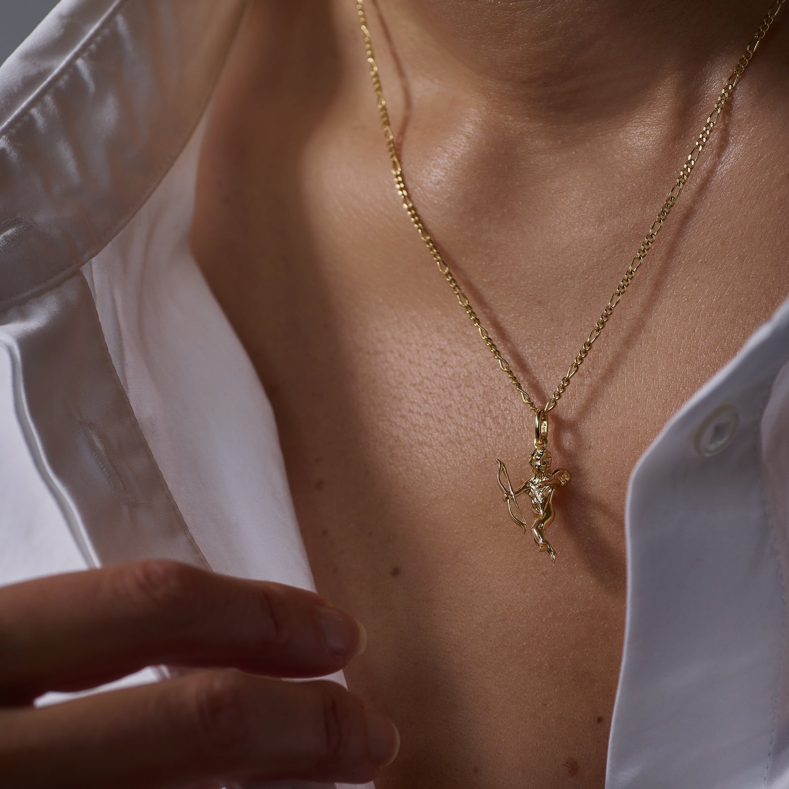 Gold necklace with an Eros Angel pendant worn by a person against a neutral background